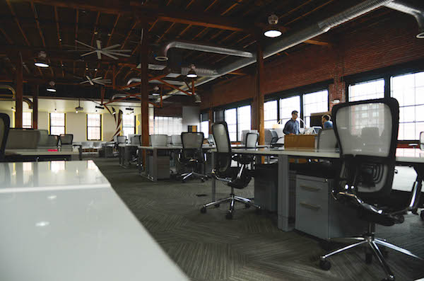 Room full of desks and chairs next to each other, image used for Ari Monkarsh blog on why you should use a coworking space