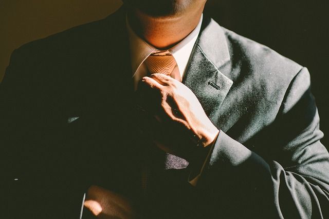 Image of man in a suit, straightening his tie, only his chin is visible. Used for Ari Monkarsh's blog on how to think like a successful businessman